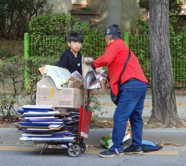 백현준군이 땅에 떨어진 폐지 상자를 들어 어르신의 손수레 위로 올리고 있다. 배병혁씨 제공