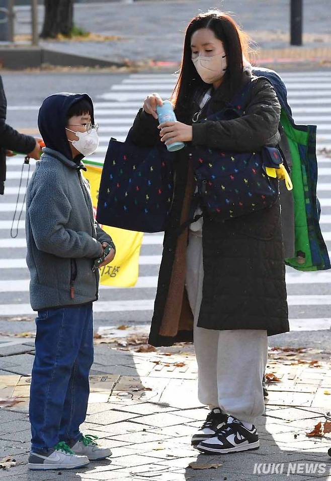 7일 아침 송파구 가락동의 한 초등학교 앞에서 어머니가 아들에게 보온병을 건네고 있다.