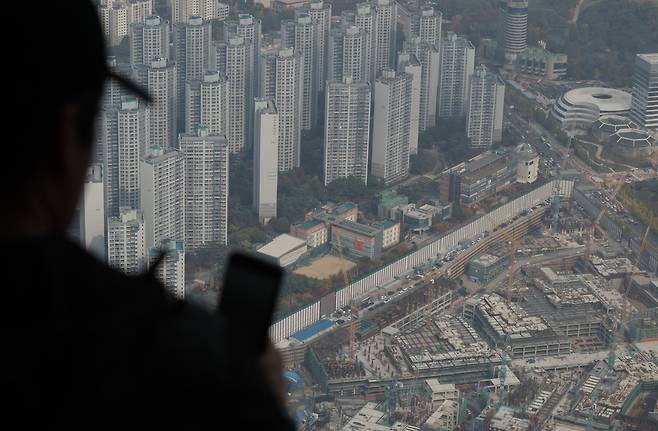 서울 송파구 서울스카이를 찾은 관람객들이 전망대 너머 아파트 단지와 재건축 진행 단지를 바라보고 있다./뉴스1