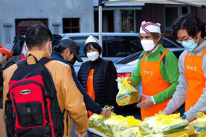 노숙인들에게 도시락을 나눠주는 김하종 신부와 ‘안나의 집’ 직원들, 자원봉사자들. 코로나 사태 이후로 실내 배식 대신 안나의 집 맞은편 성당 마당에서 도시락을 주고 있다./이신영 영상미디어 기자