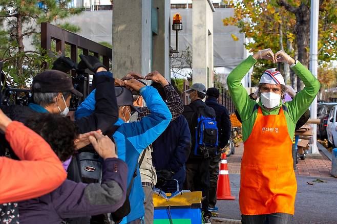 김하종 신부가 성당 앞에서 배식을 기다리는 노숙인들에게 “안녕하십니까! 사랑합니다! 건강하세요!”라고 외치고는 두 팔을 머리 위로 들어 올려 하트 모양을 만들었다./이신영 영상미디어 기자