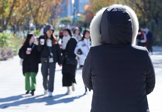 비가 그치며 서울 최저기온이 1도까지 떨어진 10일 서울 종로구 광화문광장에서 한 시민이 외투 모자를 쓰고 걷고 있다. /연합뉴스