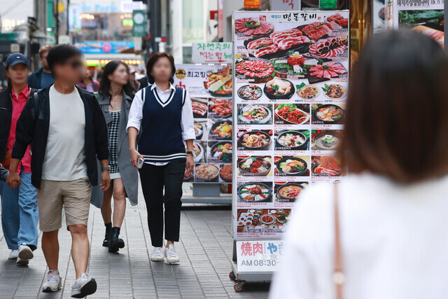 지난달 9일 서울 중구 명동에서 식당 입간판들 사이로 행인들이 지나가는 모습. 연합뉴스