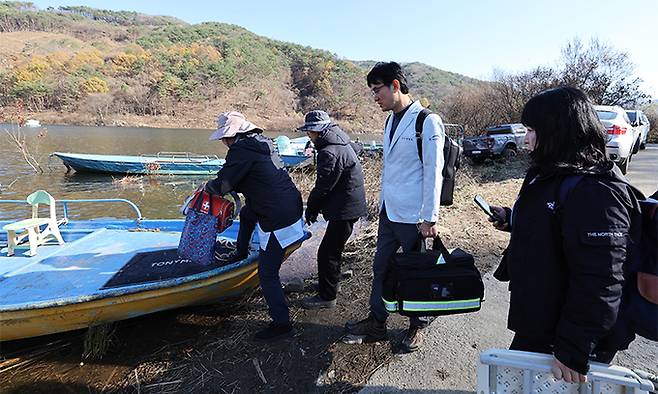 양창모 호호방문진료센터 원장(왼쪽 세번째)과 최희선 간호사(왼쪽), 최재희 케어 매니저(오른쪽)가 7일 강원 춘천시 동면 신이리 뱃길에서 소양강댐 수몰지역 마을로 방문진료를 가기 위해 진료도구 등이 담긴 큼지막한 왕진가방을 들고 보트에 오르고 있다. 춘천=남정탁 기자