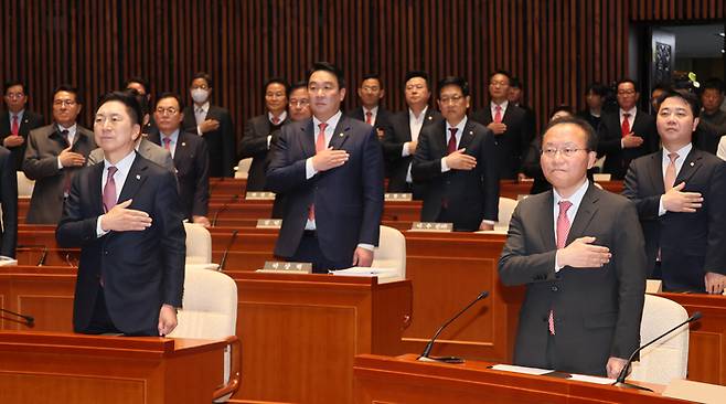 국민의힘 김기현 대표(앞줄 왼쪽)와 윤재옥 원내대표(오른쪽)이 13일 국회에서 열린 의원총회에서 국기에 경례하고 있다. 연합뉴스