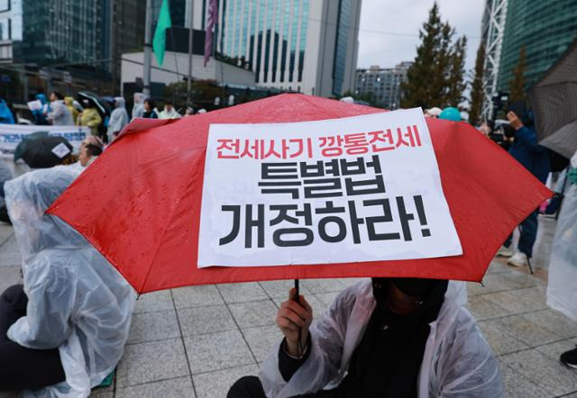 지난달 전세사기·깡통전세 피해자 전국대책위원회 주최로 서울 종로구 보신각 앞에서 열린 '전세사기 피해자 집중 집회' 참가자가 비가 오는 날씨에 메시지가 적힌 팻말을 우산에 부착한 채 집회를 이어가고 있는 모습. 연합뉴스