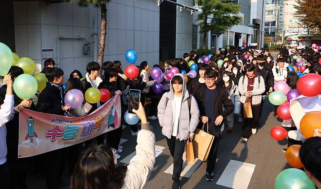 Teachers and students at Gwangnam High School in Gwangjin-gu, eastern Seoul, cheer for test takers on the eve of the Suneung, or the nation’s college entrance exam, Wednesday. (Joint Press Corps)