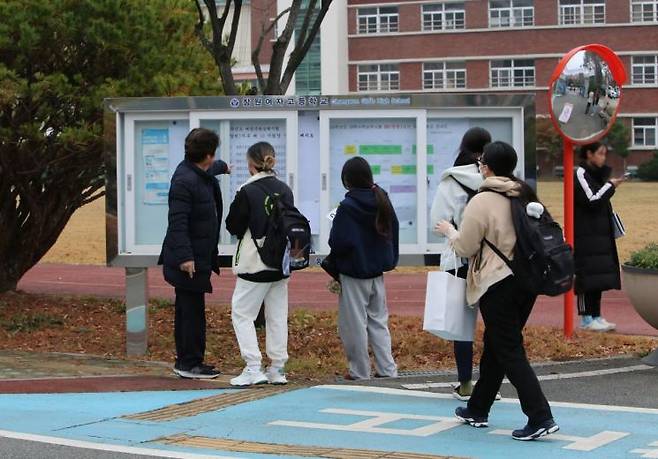 경남 창원여고에서 수능 시험을 치를 수험생들이 감독관의 도움을 받아 고사장을 확인하고 있다. [사진=이세령 기자]