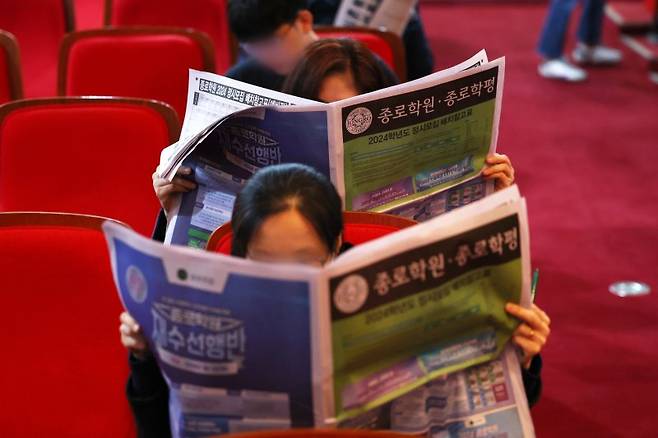 지난 17일 서울 광진구 세종대학교 대양홀에서 열린 종로학원 2024 수능 결과 및 정시합격점수 예측 설명회에서 학생과 학부모가 2024학년도 정시모집 배치 참고표를 살펴보고 있다. 연합뉴스