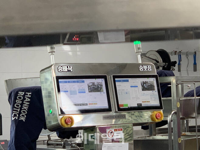 22일 오전 서울 성북구 숭곡중학교 급식실에 배치된 급식 로봇이 조리를 하고 있다. 제어PC모니터에 학생들이 지어준 이름인 ‘숭바삭’, ‘숭뽀끔’ 팻말이 붙어 있다. (사진=김윤정 기자)