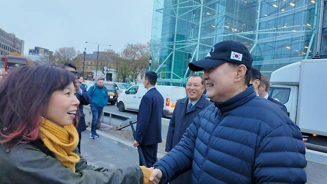 영국을 국빈 방문 중인 윤석열 대통령이 21일(현지시간) 런던 시내를 산책하던 중 지나가던 시민(일본인)이 다가와 악수를 청하자 악수하고 있다. 윤 대통령이 쓴 모자는 산책 시 항상 착용하는 천안함 모자 ⓒ대통령실