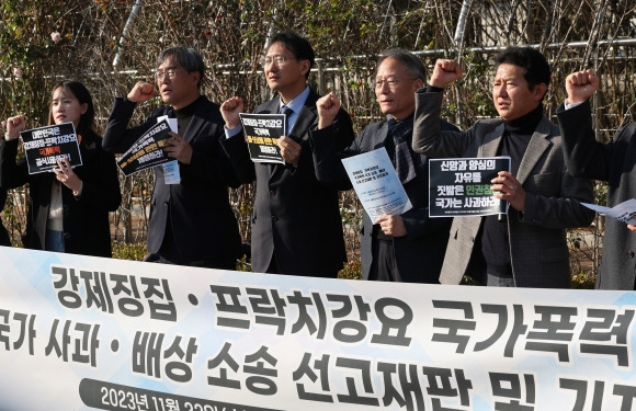 전두환 정권 시절 고문을 받고 프락치 활동을 강요당한 피해자 박만규(오른쪽 두번째) 목사와 관계자들이 소송 후 열린 기자회견에서 구호를 외치고 있다. 2023.11.22. 연합뉴스