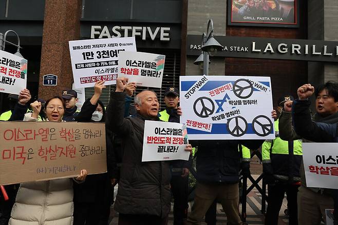 23일 오전 서울 종로구 주한이스라엘대사관 앞에서 열린 ‘이스라엘은 반인도적 전쟁을 끝내라’ 기자회견에서 참가자들이 이스라엘 국기 위에 평화 메시지를 붙이는 행위극을 하고 있다. 백소아 기자