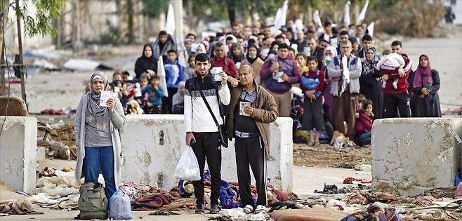 < 신분증 들고 피신하는 팔 주민들 > 이스라엘의 계속된 공습을 피해 남부로 대피하려는 가자지구 팔레스타인 주민들이 22일(현지시간) 신분증을 들어보인 채 구역 경계선 뒤에 대기하고 있다.  /AP연합뉴스