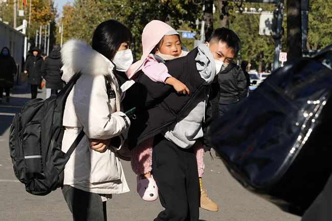 24일 중국 베이징아동병원에서 한 남성이 마스크를 쓴 채 어린이를 업고 나오고 있다. AP 뉴시스