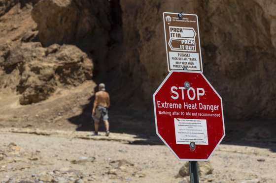 한 관광객이 지난 7월 11일 미 캘리포니아주 데스밸리 국립공원에서 극심한 더위를 경고하는 표지판을 지나가고 있다. AP=연합뉴스