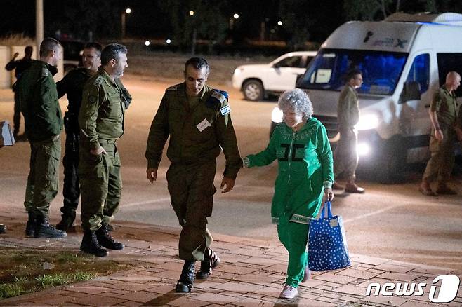 인질 루스 먼더가 지난 24일 이스라엘에 도착한 직후 이스라엘 군인과 함께 걸어가고 있다. 2023.11.25 ⓒ 로이터=뉴스1 ⓒ News1 정지윤 기자