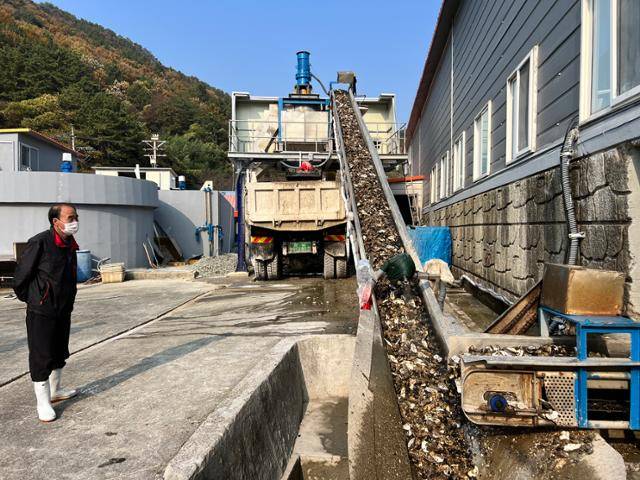 23일 경남 통영 소재 굴 작업장의 직원이 분쇄를 위해 컨베이어 벨트를 타고 이동 중인 굴 껍데기를 바라보고 있다. 통영=변태섭 기자