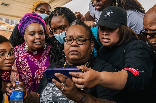 미네소타주 미니애폴리스에서 시민들이 25일 조지 플로이드를 숨지게 한 백인 경찰 데릭 쇼빈의 1심 재판 중계를 휴대폰으로 지켜보고 있다. /AFP 연합