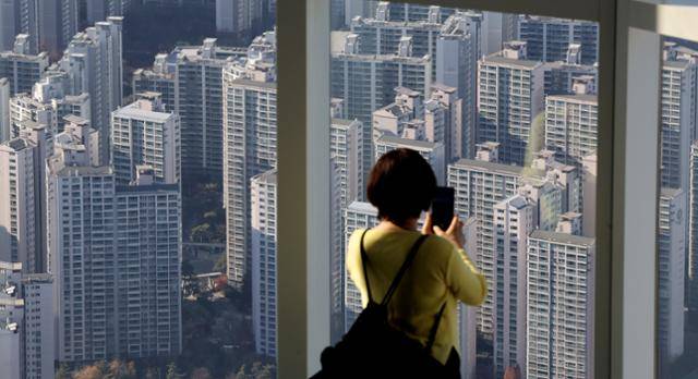 지난달 30일 오후 서울 송파구 롯데월드타워 전망대를 찾은 관람객이 아파트 단지를 바라보고 있다. 뉴스1