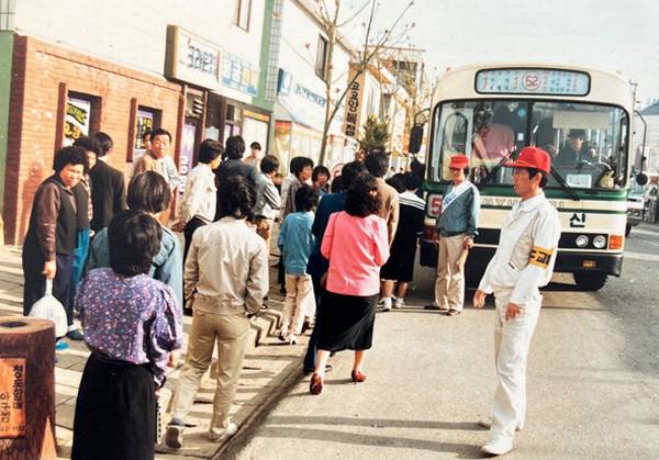 1963년 직할시 출범과 함께 탄생한 부산 시내버스는 도심은 물론 고지대와 외곽지대를 가리지 않고 운행하며 시민의 발 역할을 톡톡히 해냈다. 사진은 1980년대 52번 버스에 승차하는 승객들과 이를 지켜보는 교통지도원.  부산광역시버스운송사업조합 제공