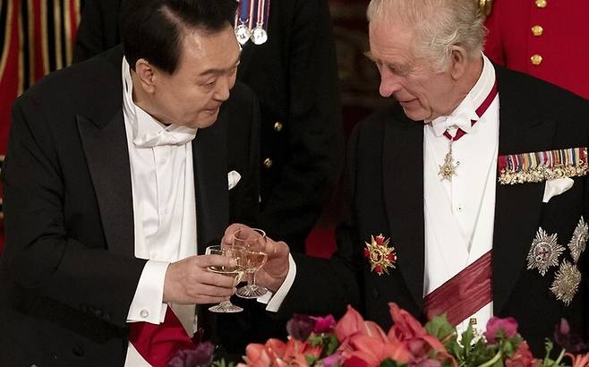 윤석열 대통령(왼쪽)과 찰스 3세 영국 국왕이 지난달 21일(현지시각) 영국 버킹엄 궁전에서 열린 만찬에서 잔을 부딪히고 있다. AP 연합뉴스