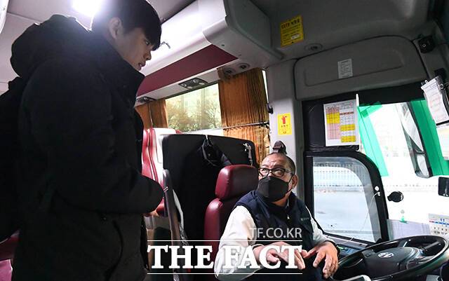버스 기사가 임시 정류장을 이용하는 방법을 승객에게 알려주고 있다.