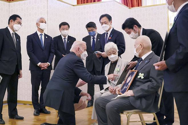 조 바이든(앞줄 왼쪽) 미국 대통령이 지난 23일 일본 도쿄 모토아카사카 영빈관에서 납북 피해자 가족들을 만나 무릎을 꿇은 자세로 피해자 사진을 가리키며 이야기를 나누고 있다. 이날 만남에서 바이든 대통령은 피해자 가족과 포옹하며 “나도 (가족을 잃은) 당신들 마음을 잘 안다”고 위로한 것으로 전해졌다. /로이터 연합뉴스