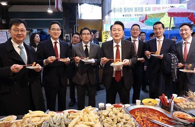 윤석열 대통령이 6일 부산 중구 깡통시장을 방문해 기업인들과 떡볶이를 맛보고 있다. 왼쪽부터 최재원 SK 수석부회장, 이재용 삼성전자 회장, 조현준 효성 그룹 회장, 윤 대통령, 구광모 LG그룹 회장, 김동관 한화그룹 부회장, 정기선 HD현대 부회장. (대통령실통신사진기자단) ⓒ뉴시스