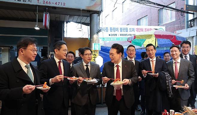 윤석열 대통령이 6일 부산 중구 깡통시장에서 재계 총수들과 분식을 맛보고 있다. 왼쪽부터 최재원 SK 수석부회장, 이재용 삼성전자 회장, 조현준 효성그룹 회장, 윤 대통령, 구광모 LG그룹 회장, 김동관 한화 그룹 부회장, 정기선 HD현대 부회장, 조원태 한진그룹 회장. 연합뉴스.