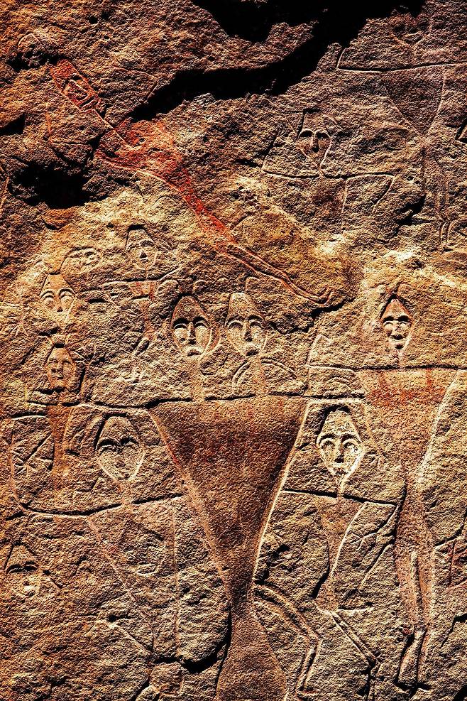 사진 위쪽 누운 사람의 몸이 붉은 컬러를 칠한 것이 남아있는 비교적 후대에 그려진 암각화로 위구르인의 정면 얼굴이 묘사되어 있다. 역삼각형의 몸통은 여자를 상징한다. 캉지아시멘치, 중국, 2019/ 사진가 강운구
