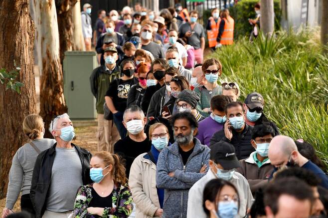 24일(현지시간) 호주 시드니의 한 신종 코로나바이러스 감염증(코로나19) 백신접종소 앞에서 마스크를 착용한 시민들이 줄지어 차례를 기다리고 있다. /AFP 연합뉴스