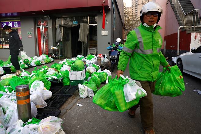 23일 '중국판 배달의 민족'인 메이퇀의 배달원이 음식을 나르고 있다. 베이징 당국이 식당 취식 금지령을 내리는 등 방역 기준이 강화되자 현지에서 배달 주문이 폭증하고 있다. /로이터 연합뉴스
