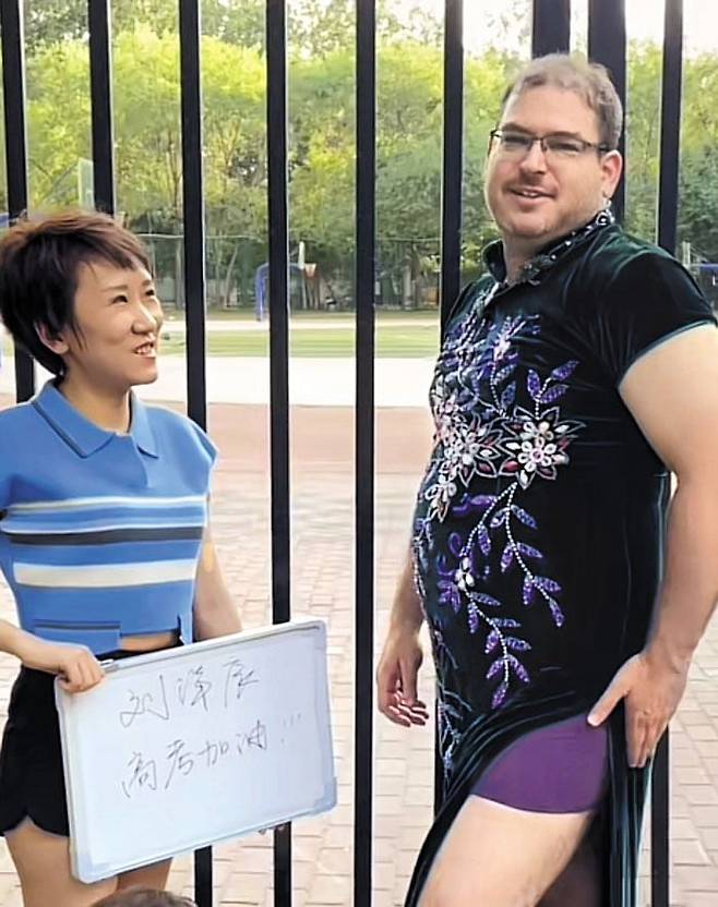 성공의 상징 '보라색 속옷' 입고 수험생 응원 - 한 캐나다 남성(오른쪽)이 랴오닝성의 대입 시험장 앞에서 중국 전통 의상 치파오와 보라색 속옷을 입고 수험생을 응원하고 있다. 중국어로 ‘캐나다’에 들어가는 ‘가(加)’자 역시 ‘가점’의 의미로 시험 성공을 뜻한다. /더우인