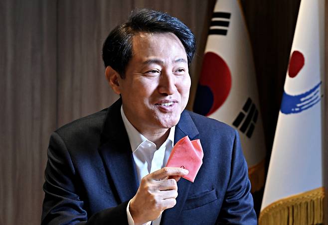 Seoul Mayor Oh Se-hoon poses for a photo during an interview with The Korea Herald at Seoul City Hall, showing a "sky coral" handkerchief, the color his administration chose as this year's "Color of Seoul," derived from the pink sky when the sun sets over the Han River. (Im Se-jun/The Korea Herald)