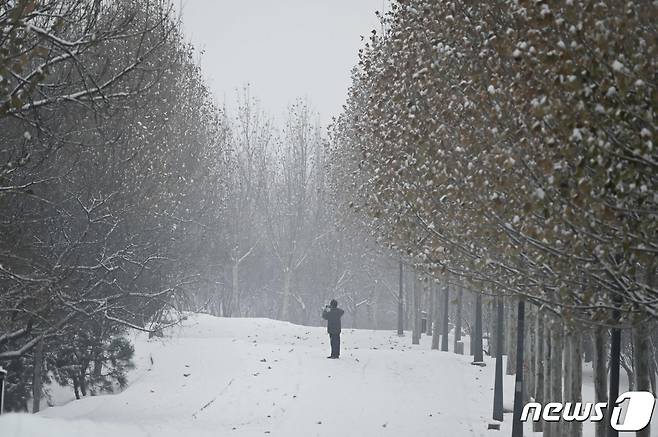 13일 중국 베이징에 눈이 내리는 가운데 한 남성이 사진을 찍고 있다. 2023.12.13 ⓒ AFP=뉴스1 ⓒ News1 정지윤 기자