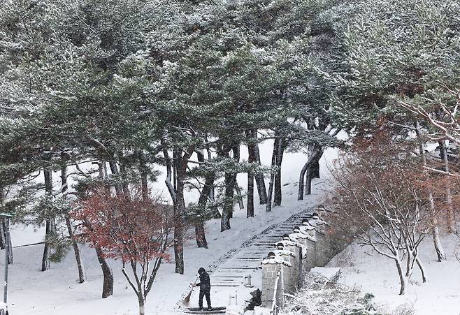 한 시민이 등산로 계단에 쌓인 눈을 치우고 있다. 연합뉴스