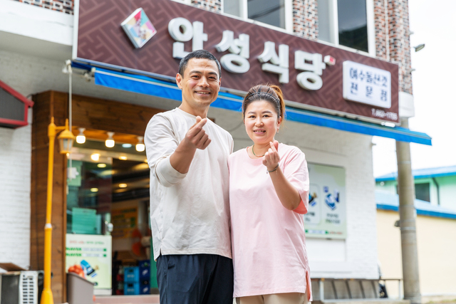 전남 여수 ‘안성식당’을 운영하는 부부가 식당 앞에서 활짝 웃으며 손하트를 지어보이고 있다. 이윤화