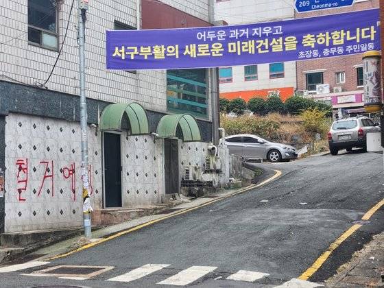 지난 14일 부산 완월동에 고층 건물 재개발 계획 승인 및 성매매 영업장 철거를 반기는 주민 현수막이 걸려있다. 김민주 기자