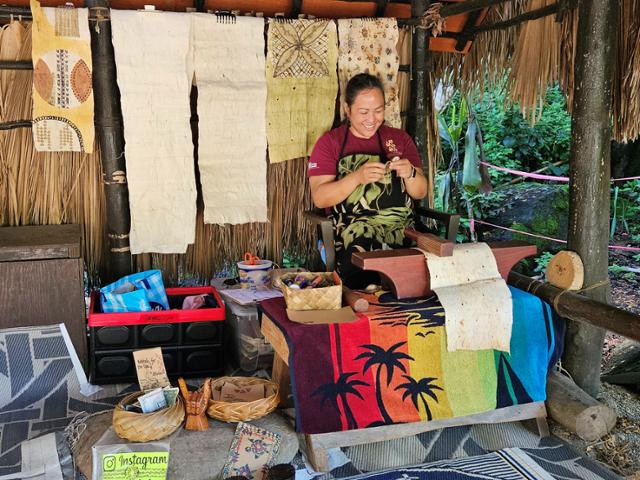 와이메아 계곡 산책로에서 한 하와이 전통공예 장인이 작업을 하며 방문객에게 미소짓고 있다.