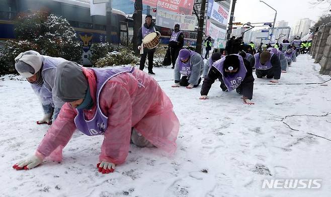 [서울=뉴시스] 조성봉 기자 = 눈이 내린 20일 오전 서울 여의도 국회 앞에서 이태원참사 유가족과 종교인들이 이태원참사 특별법 국회 본회의 통과를 촉구하며 오체투지를 하고 있다. 2023.12.20. suncho21@newsis.com