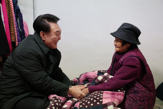 President Yoon Suk Yeol, left, speaks with a senior citizen who lives alone in a multiunit house in Jungnang District, eastern Seoul, on Thursday, to provide winter supplies amid freezing temperatures this week. [PRESIDENTIAL OFFICE]