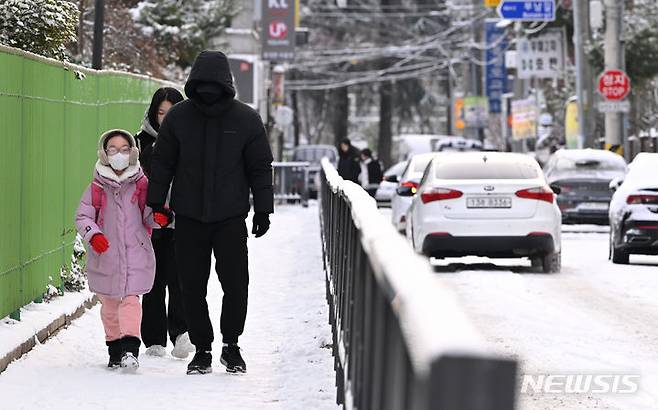 [광주=뉴시스] 이영주 기자 = 광주지역에 밤사이 많은 눈이 내린 21일 오전 광주 북구 문흥동 인도에서 한 초등학생과 학부모가 등교하고 있다. 2023.12.21. leeyj2578@newsis.com