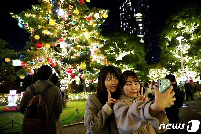23일 일본 도쿄에서 시민들이 화려한 크리스마스 트리 앞에서 사진을 찍고 있다. 2021.11.23/ ⓒ 로이터=뉴스1 ⓒ News1 박재하 기자