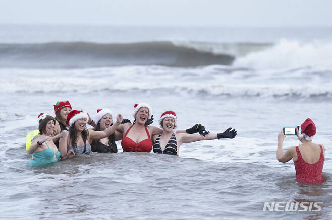 [롱샌드비치=AP/뉴시스] 성탄절인 25일(현지시각) 영국 롱샌드비치에서 크리스마스 수영 대회가 열려 참가자들이 기념 사진을 찍고 있다. 2023.12.26.