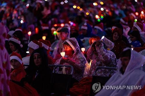 우비 쓰고 캐럴 행사 지난 24일 호주 멜버른에서 열린 캐럴 공연 행사에서 참가자들이 우비를 쓴 채 공연을 보고 있다.
[EPA 연합뉴스 자료사진. 재판매 및 DB 금지]