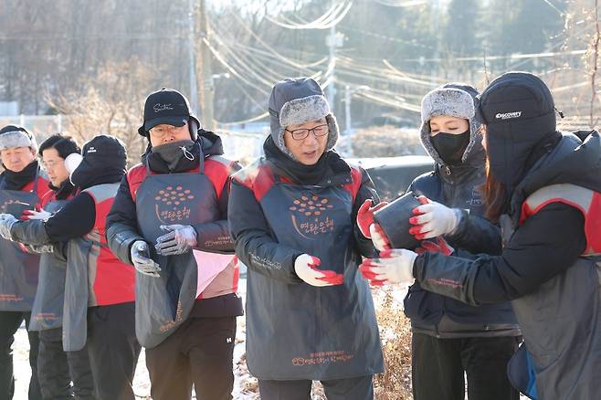 롯데건설 박현철 부회장(오른쪽 세 번째)과 배우 정애리(오른쪽 두 번째)가 임직원들과 함께 연탄을 나르고 있다. 사진제공 ｜ 롯데건설