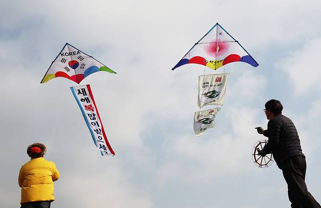 People fly kites with New Year's greetings and drawings of 2024's blue dragon to commemorate the upcoming New Year at Changryongmun of Suwon Hwaseong Fortress on Thursday. (Yonhap)