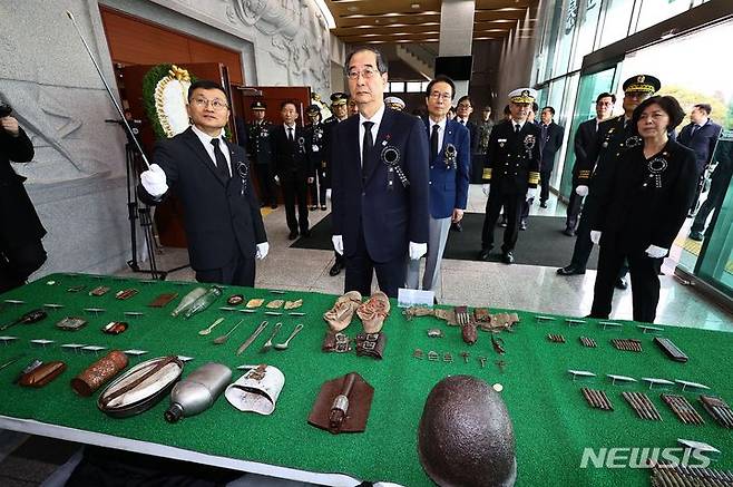 [서울=뉴시스] 사진공동취재단 = 한덕수(가운데) 국무총리가 29일 오전 서울 동작구 국립서울현충원 현충관에서 열린 6·25전사자 발굴유해 합동 봉안식에 앞서 6·25전사자 유품이 진열된 테이블 앞에서 이근원(왼쪽) 유해발굴감식단장의 설명을 듣고 있다. 2023.12.31. photo@newsis.com