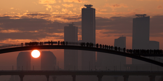 People see the New Year’s first sunrise on Seonyudo Bridge at Seonyudo Park in Yeongdeungpo District in western Seoul on Monday. [NEWS1]